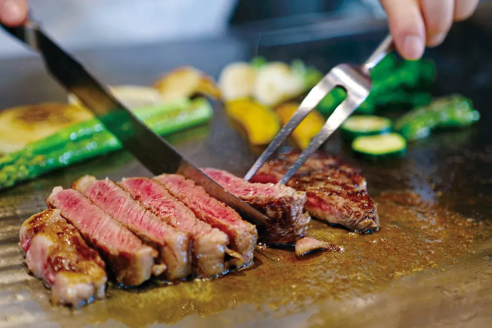 Hibachi chef using spatulas on a teppanyaki grill