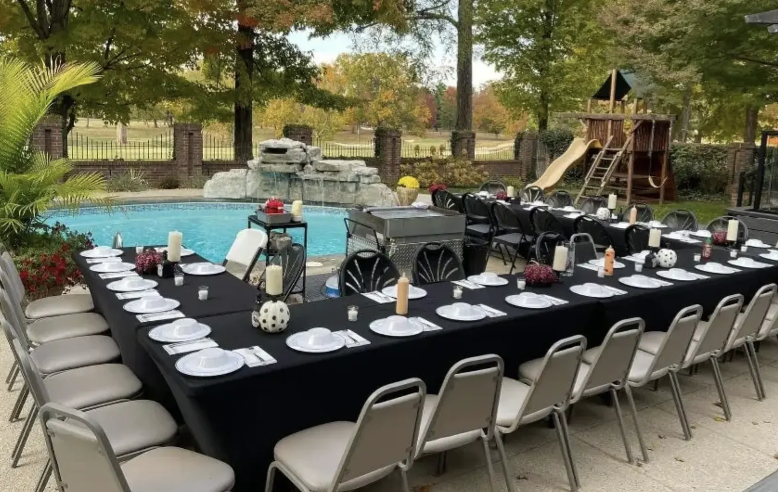 Rented tables chairs and black table cloths set up for a poolside hibachi party